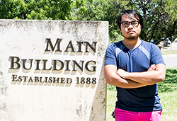 Joseph V poses next to the Main Building at St. Edward’s University