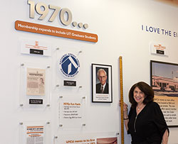 Laurie Thomas stands in front of the UFCU history wall
