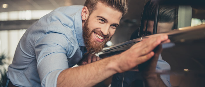 Happy man inspecting car at car dealership
