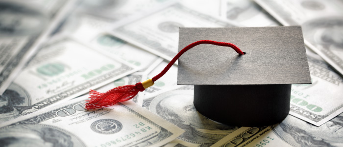 Graduation cap sitting on one hundered dollar bills