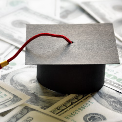 Graduation cap sitting on one hundered dollar bills