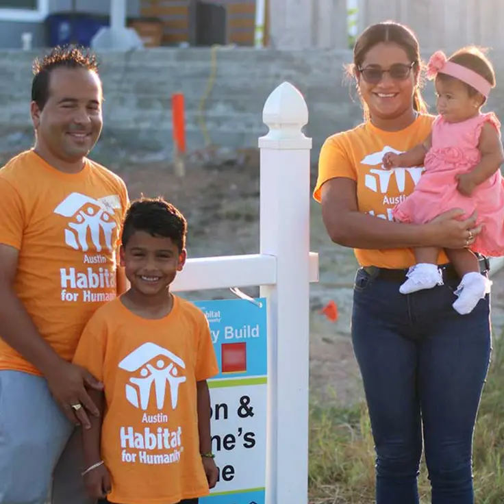 A happy family stands in front of their Habitat for Humanity Home